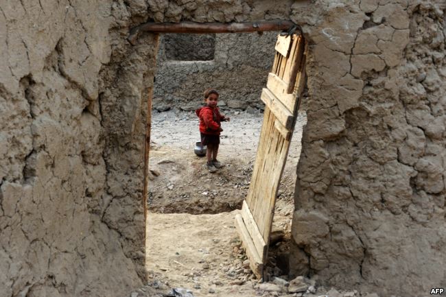 An Internally displaced Afghan child looks out from within his temporary home at a refugee camp in Kabul in December.